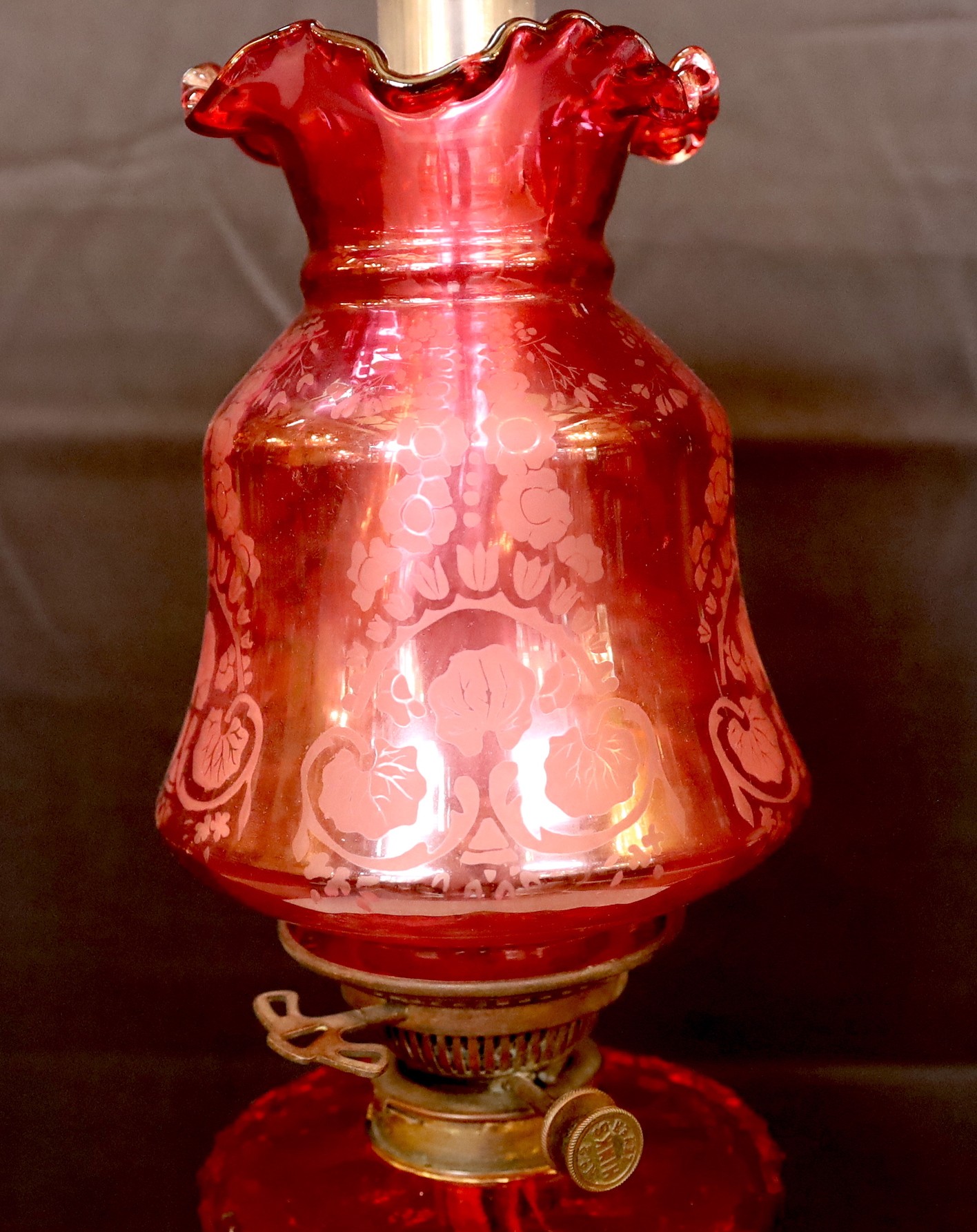 A Victorian lacquered brass fluted column oil lamp with cut ruby glass reservoir, Hinks No2 mechanism, etched cranberry glass shade and flue, height overall 86cm